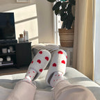 Person wearing fuzzy heart-print slippers relaxing indoors.