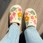 Person wearing flower-patterned slippers and jeans.