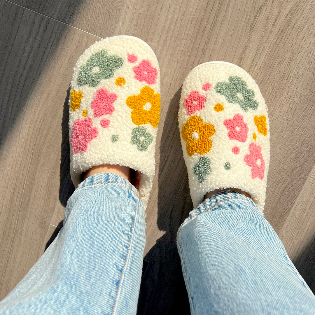Person wearing flower-patterned slippers and jeans.