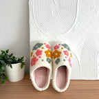 Pair of floral slippers on a wooden surface.