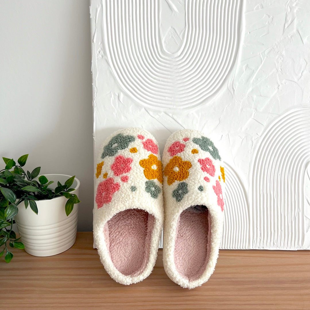 Pair of floral slippers on a wooden surface.